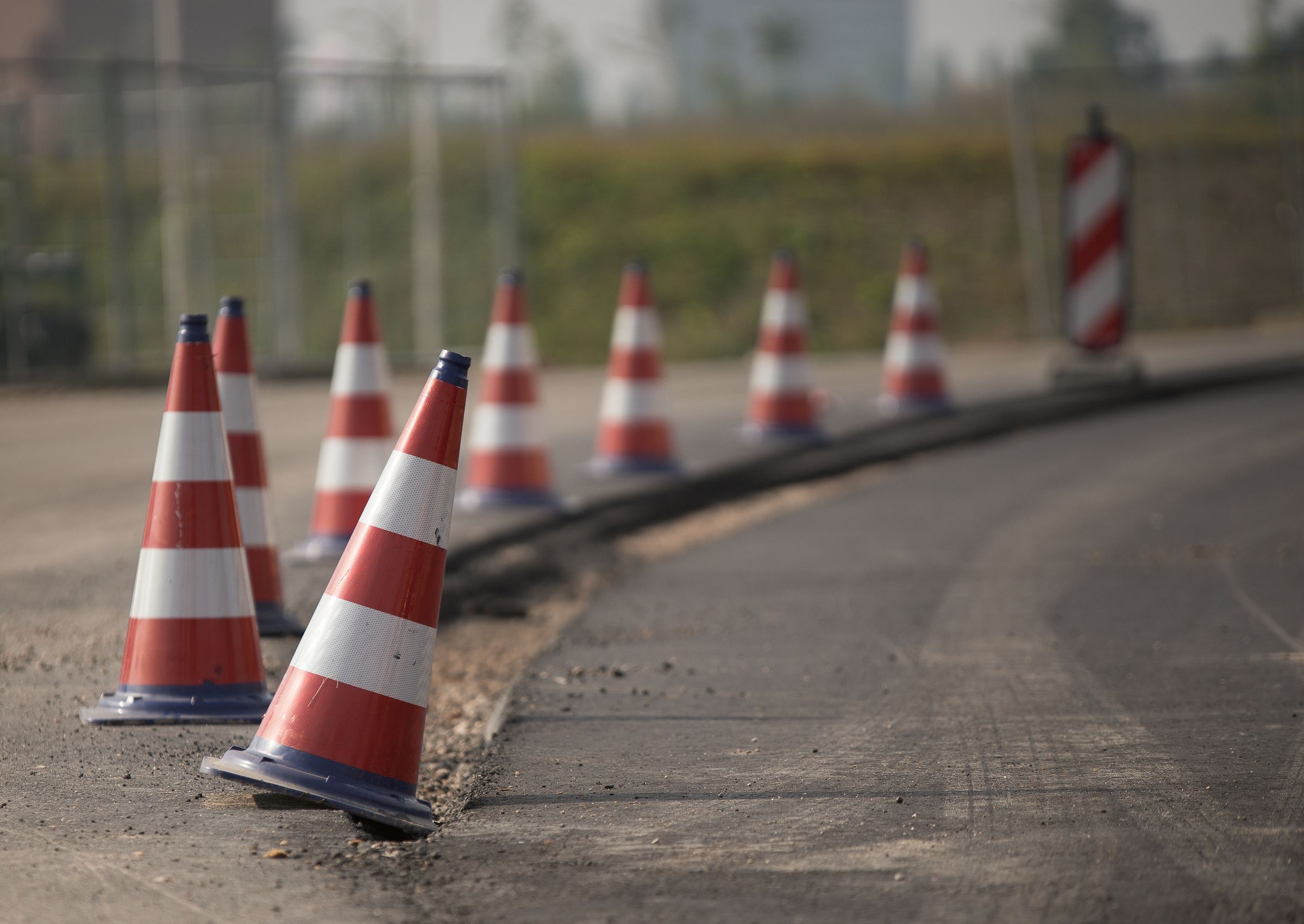 Reihe rot-weißer Leitkegel sichert bei Tageslicht den Rand einer Arbeitsstelle